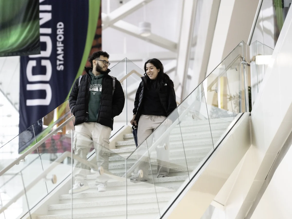 UConn Supply Chain students walking down stairs inside the Stamford School of Business.