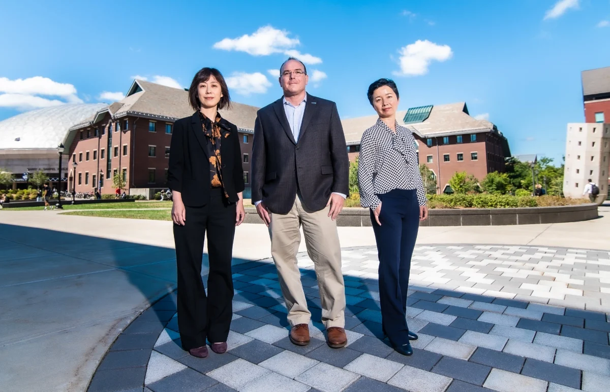 Three UConn Supply Chain Faculty standing in front of the School of Business.