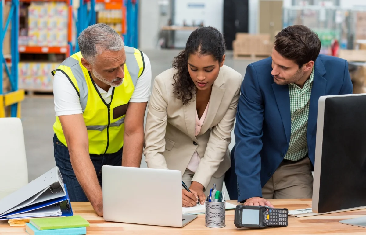 Three Supply Chain professional having discussion looking at laptop.
